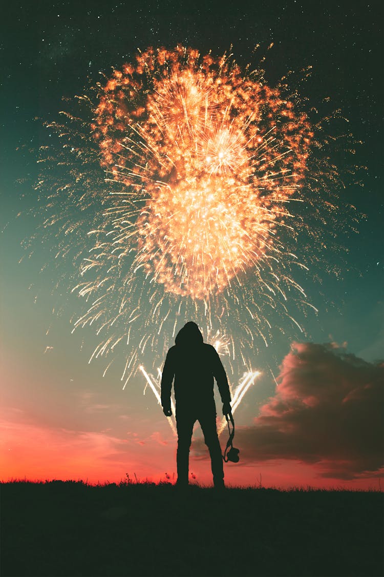 Silhouette Photo Of Standing Man Holding Camera Looking At Fireworks Display