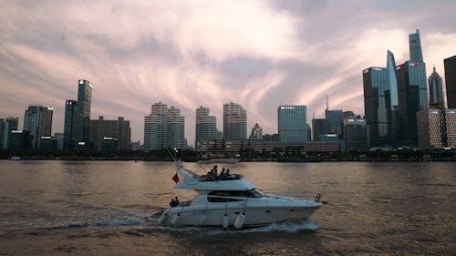 Motor Yacht Sailing near Skyscrapers in City on Sea Coast