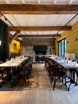 Beautiful banquet hall set for fine dining with rustic wooden beams and elegant decor.