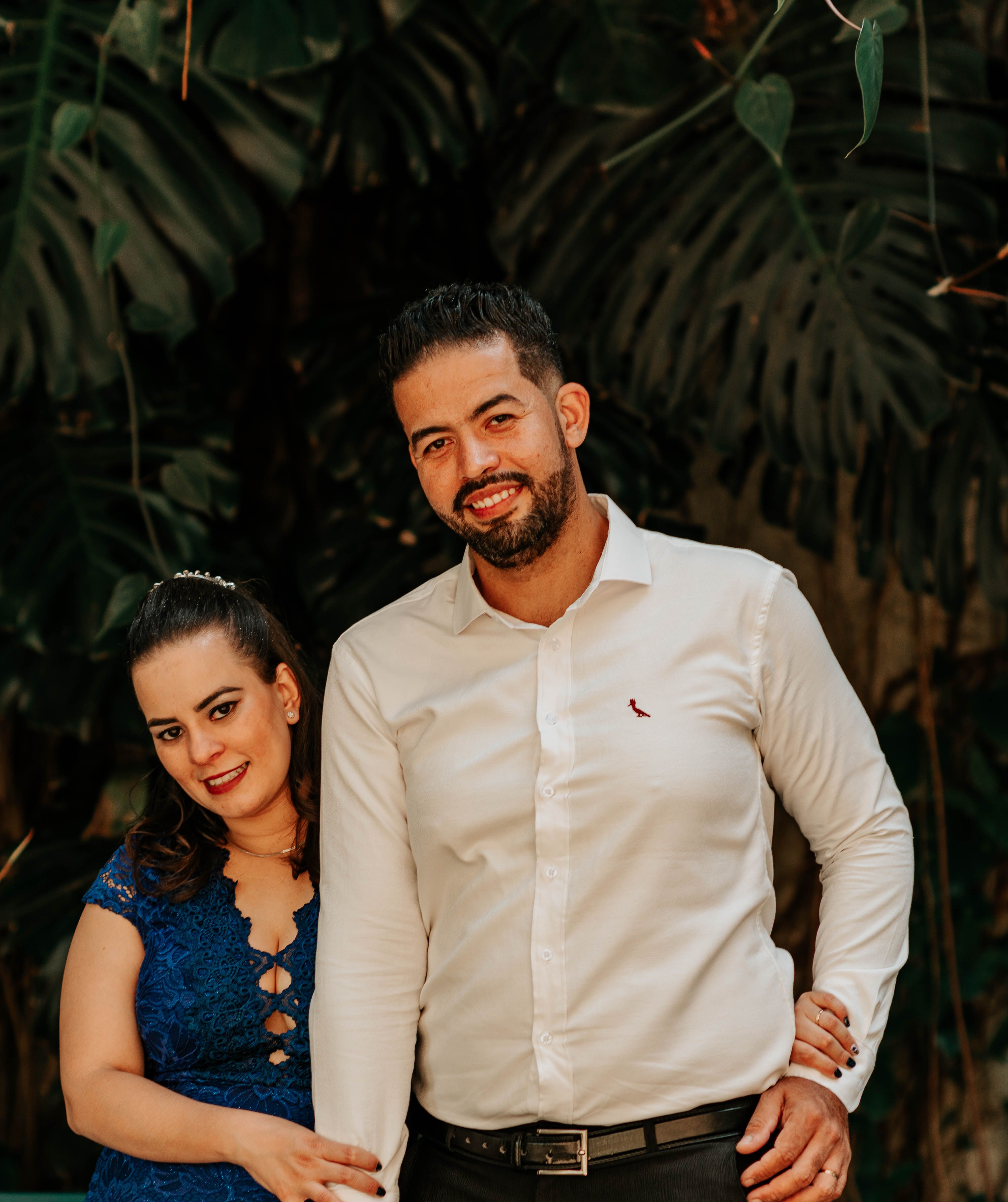 Smiling couple enjoying a moment together in a lush, tropical garden setting.