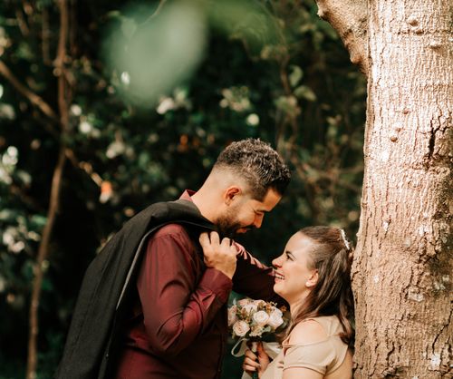 Free A couple enjoys a tender moment in a forest setting, holding a bouquet of flowers. Stock Photo
