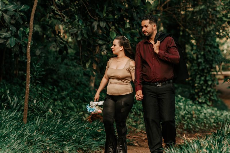 A couple strolls hand in hand along a lush forest pathway, enjoying nature's tranquility.