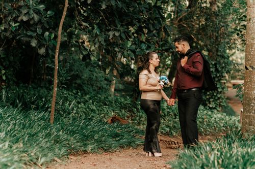 Free A couple holding hands and walking in a lush green park, symbolizing romance and togetherness. Stock Photo