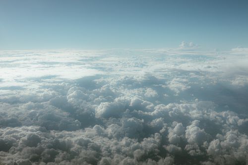 Free Serene aerial view of fluffy clouds beneath a clear blue sky, perfect for themes of tranquility and nature. Stock Photo