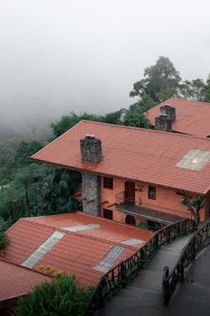 A rustic house with red roof nestled in a misty jungle environment, showcasing tropical nature.