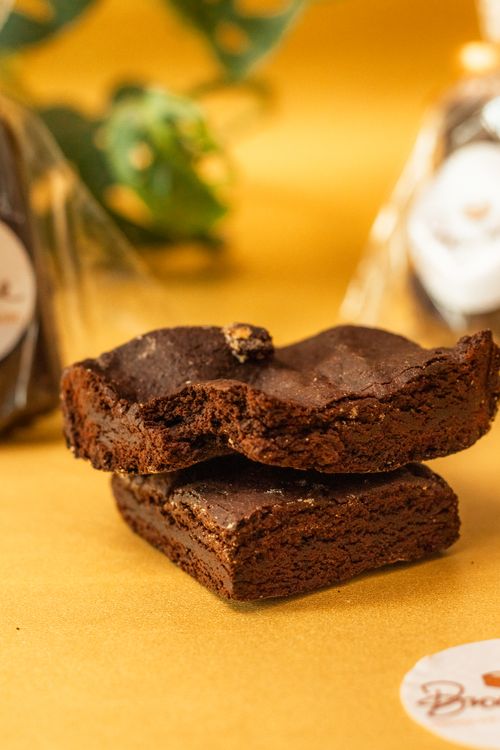 Free Close-up of delectable chocolate brownies stacked on a yellow surface, rich and inviting. Stock Photo