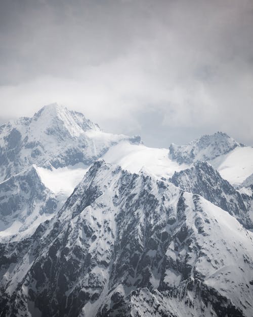 A photo of a snowy mountain range with clouds