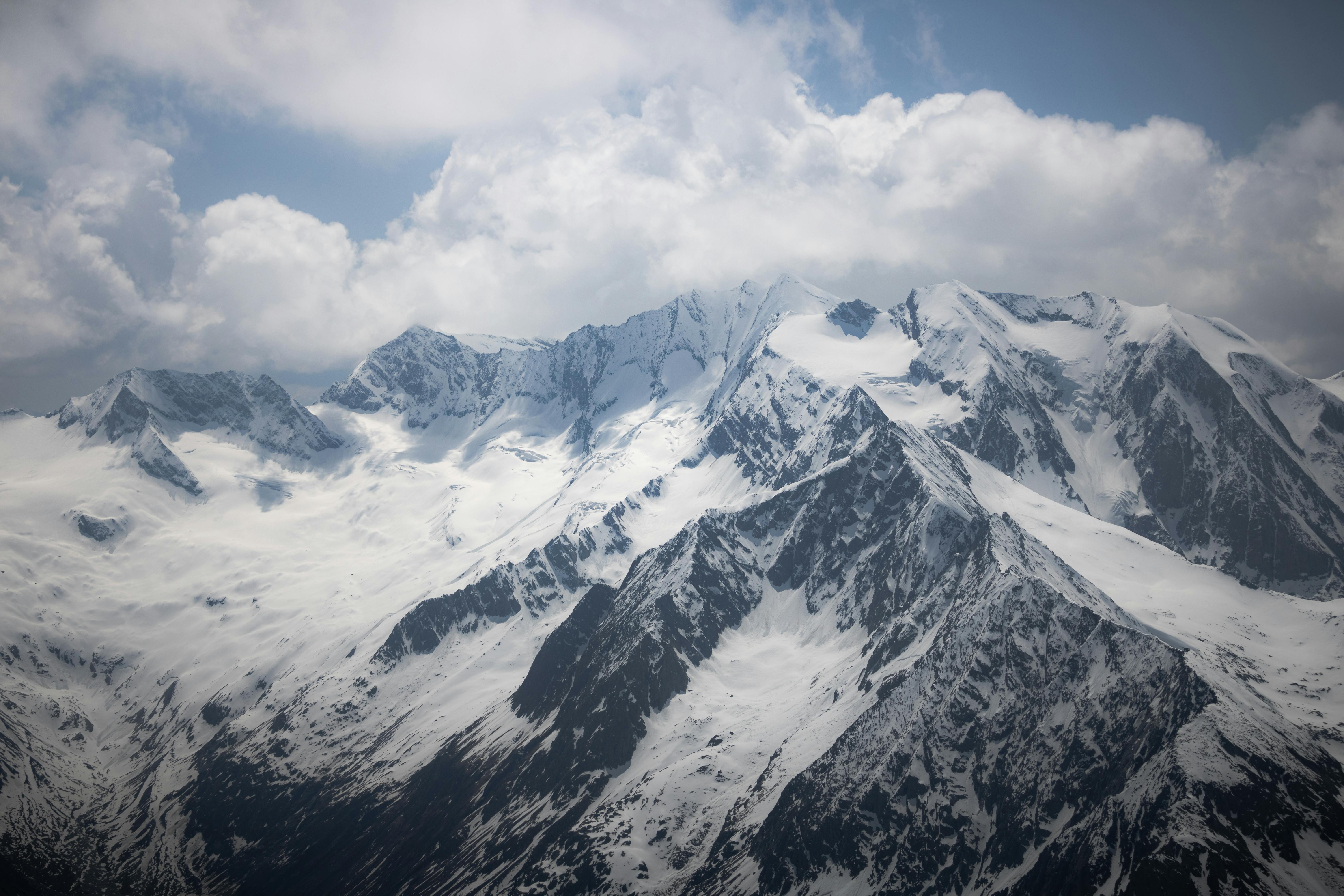 a view of a snowy mountain range with clouds