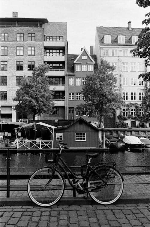 Black and White Photo of a Bicycle by a City Canal