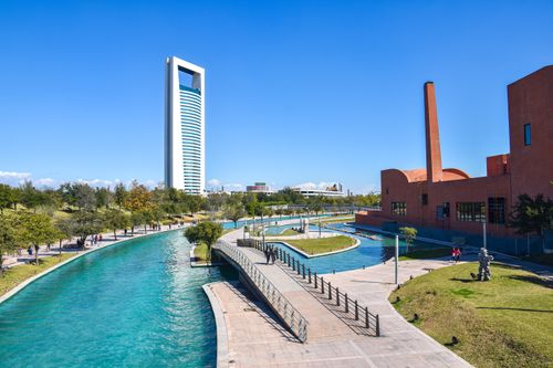 Free Scenic view of urban park in Monterrey, featuring a canal, modern architecture, and a towering skyscraper Stock Photo