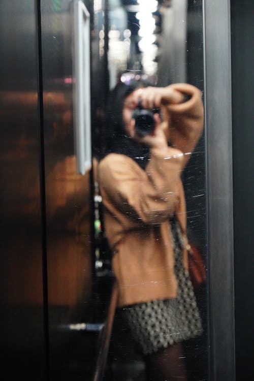 Woman in Jacket Taking Photo of Herself in Elevator