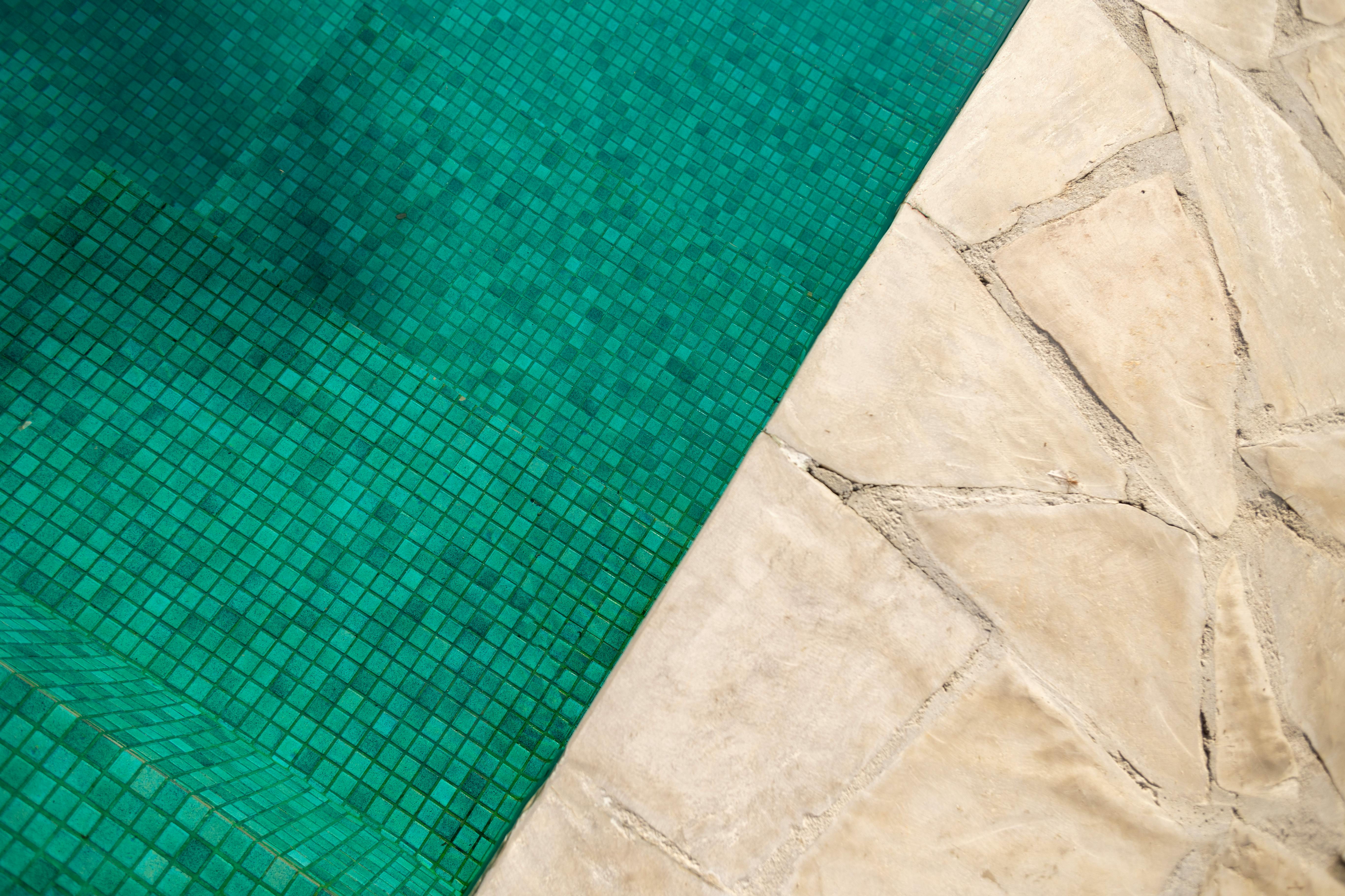 Free Top-down view of a vibrant turquoise pool beside stone pavement, ideal for vacation themes. Stock Photo