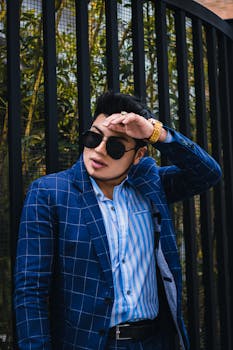 Well-dressed young man poses fashionably outdoors in a blue checked suit.