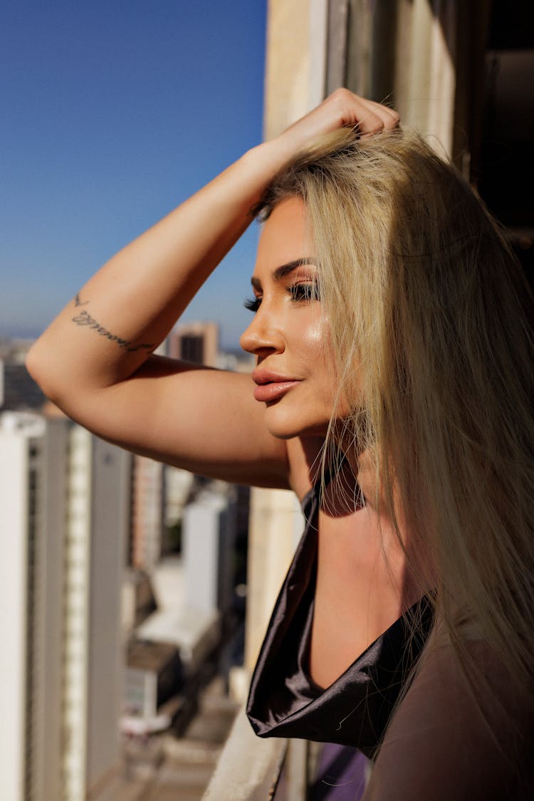 Blonde Woman With Hand In Hair Looking At City