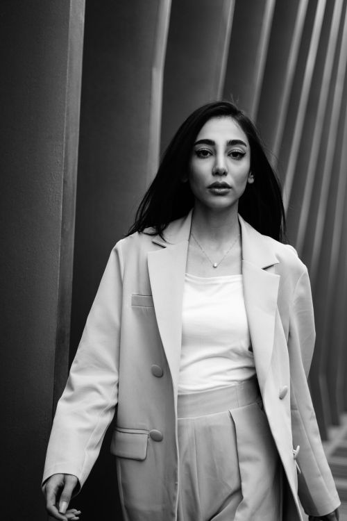 Free Black and white portrait of a woman in a suit walking through an urban corridor. Stock Photo