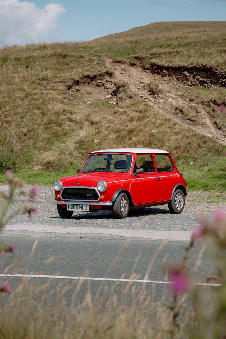 A Red Mini Parked On The Side Of The Road In The Countryside 