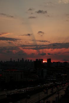 A dramatic İstanbul cityscape at dusk featuring a vibrant sunset and urban skyline silhouette.
