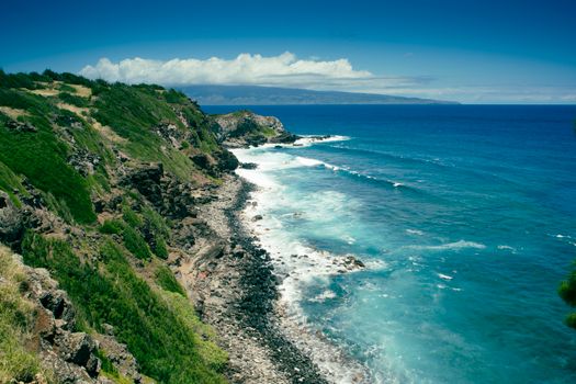 A stunning aerial view of rocky cliffs and a vibrant blue ocean meeting the horizon.