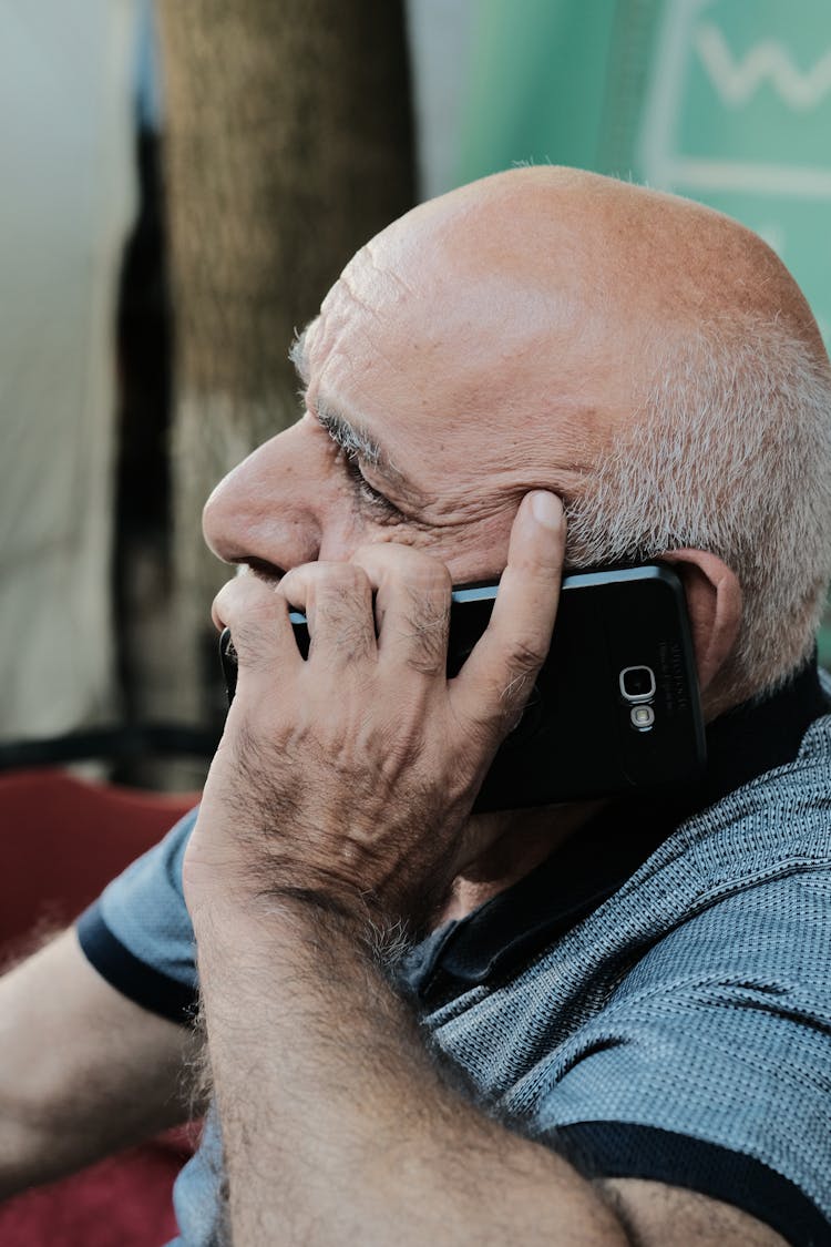 Side View Of An Elderly Man Talking On The Phone 