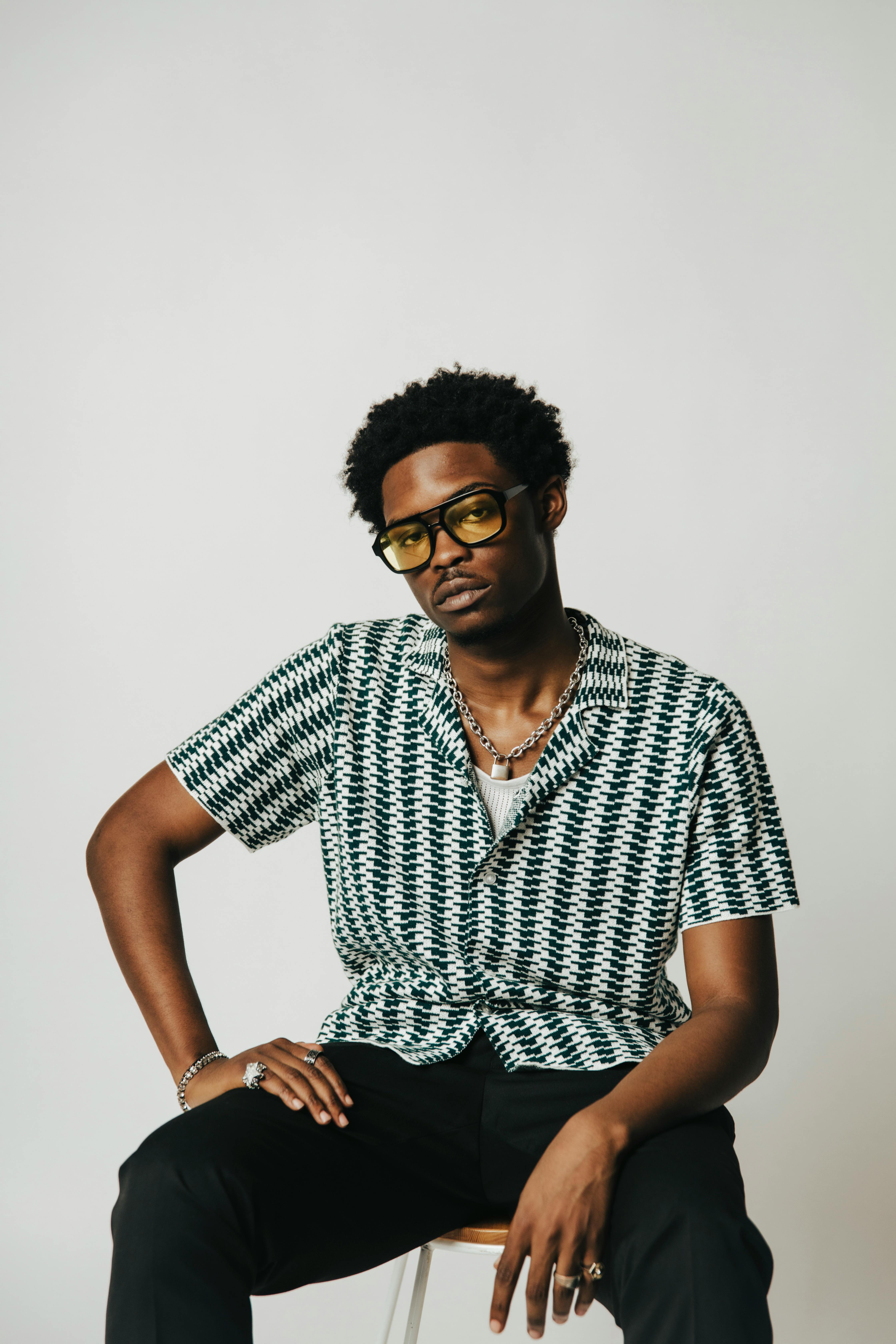 Fashionable African man poses confidently in a studio setting, highlighting modern style.