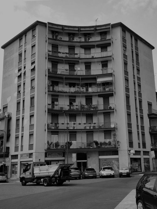 Free Monochrome photo of a multi-story residential building with vehicles on the street. Stock Photo