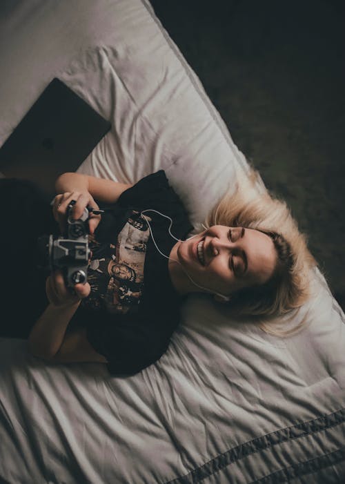 Blonde Woman Smiling, Lying Down and Using Controller