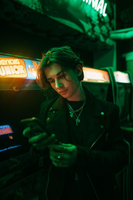 A young man enjoys a moment in a neon-lit arcade with a retro vibe.