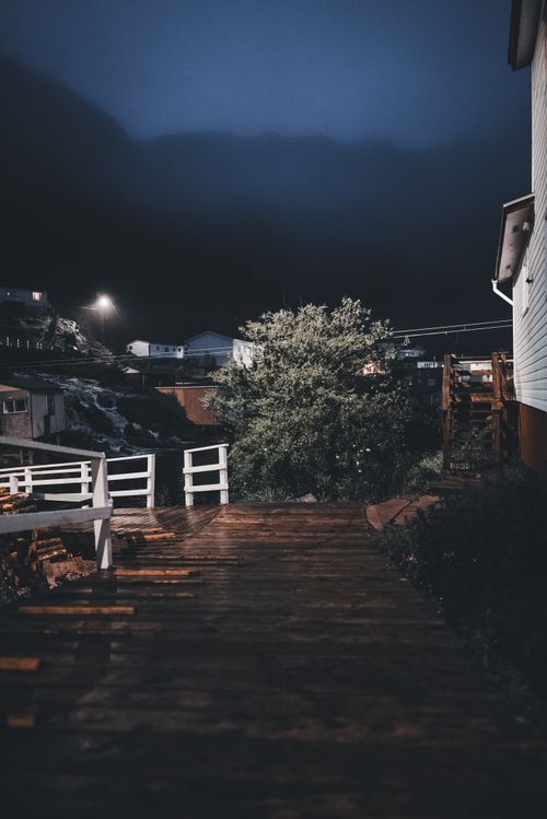 Free A serene village footpath under the night sky, with snow and wooden railings. Stock Photo