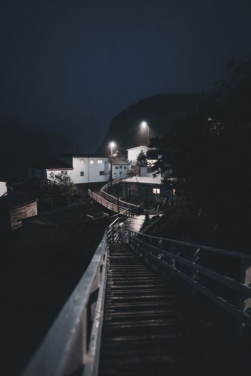 Free A dimly lit path leading through a quiet village at night under street lamps. Stock Photo