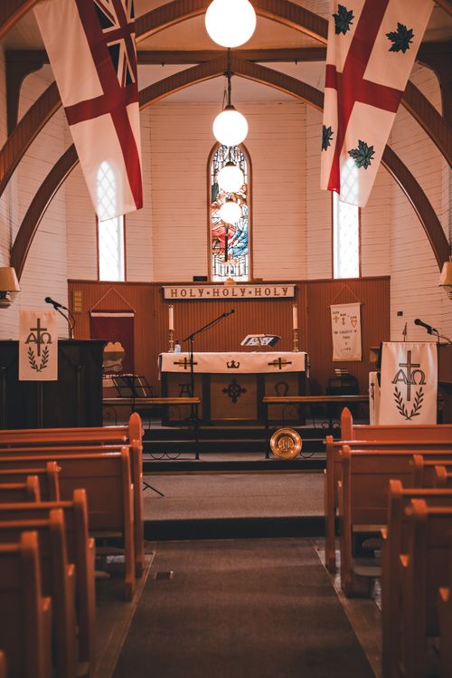 Free A serene church interior featuring an illuminated altar, colorful stained glass, and wooden pews. Stock Photo
