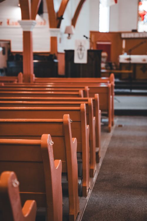 Free Peaceful view of a church interior featuring rows of pristine wooden pews, capturing a serene religious atmosphere. Stock Photo