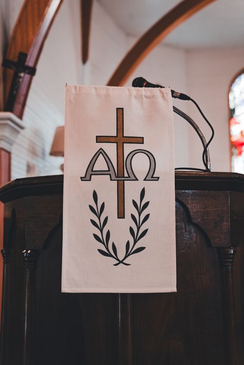 Free Intricate church pulpit adorned with a cross and Alpha Omega symbol, set within a serene worship space. Stock Photo