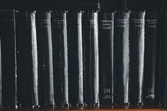 Close-up of black books on a shelf highlighting their titles.
