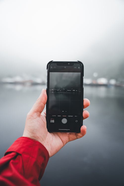 Hand Holding Cellphone and Taking Pictures of Lake