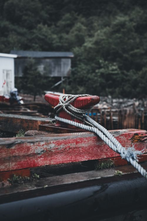 Free A close-up of a rope tied to a weathered dock, illustrating nautical themes and rustic textures. Stock Photo