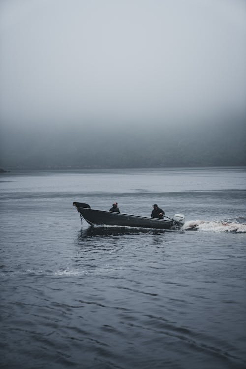 Free People in a Motorboat on a Lake in Fog Stock Photo