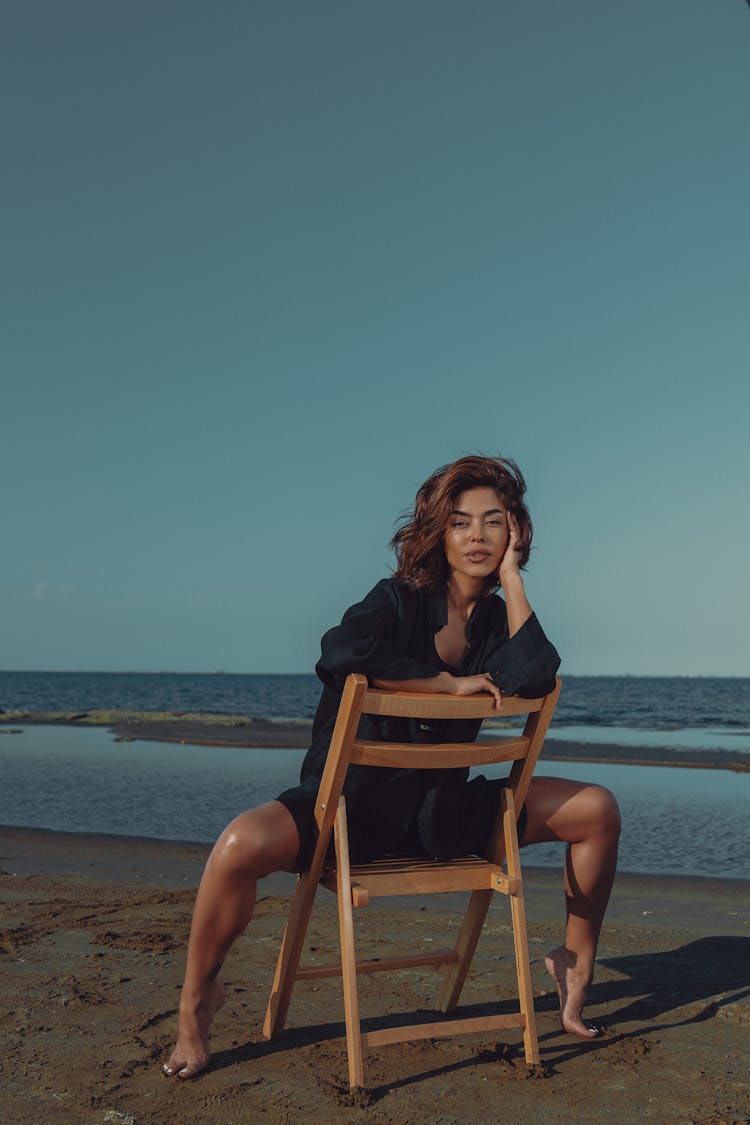 Woman Sitting On Chair On Beach And Posing