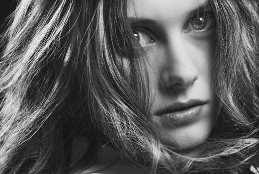 Close-up black and white portrait of a woman with expressive eyes and long hair.