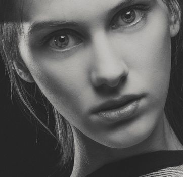 Artistic black and white portrait of a young woman with expressive eyes.