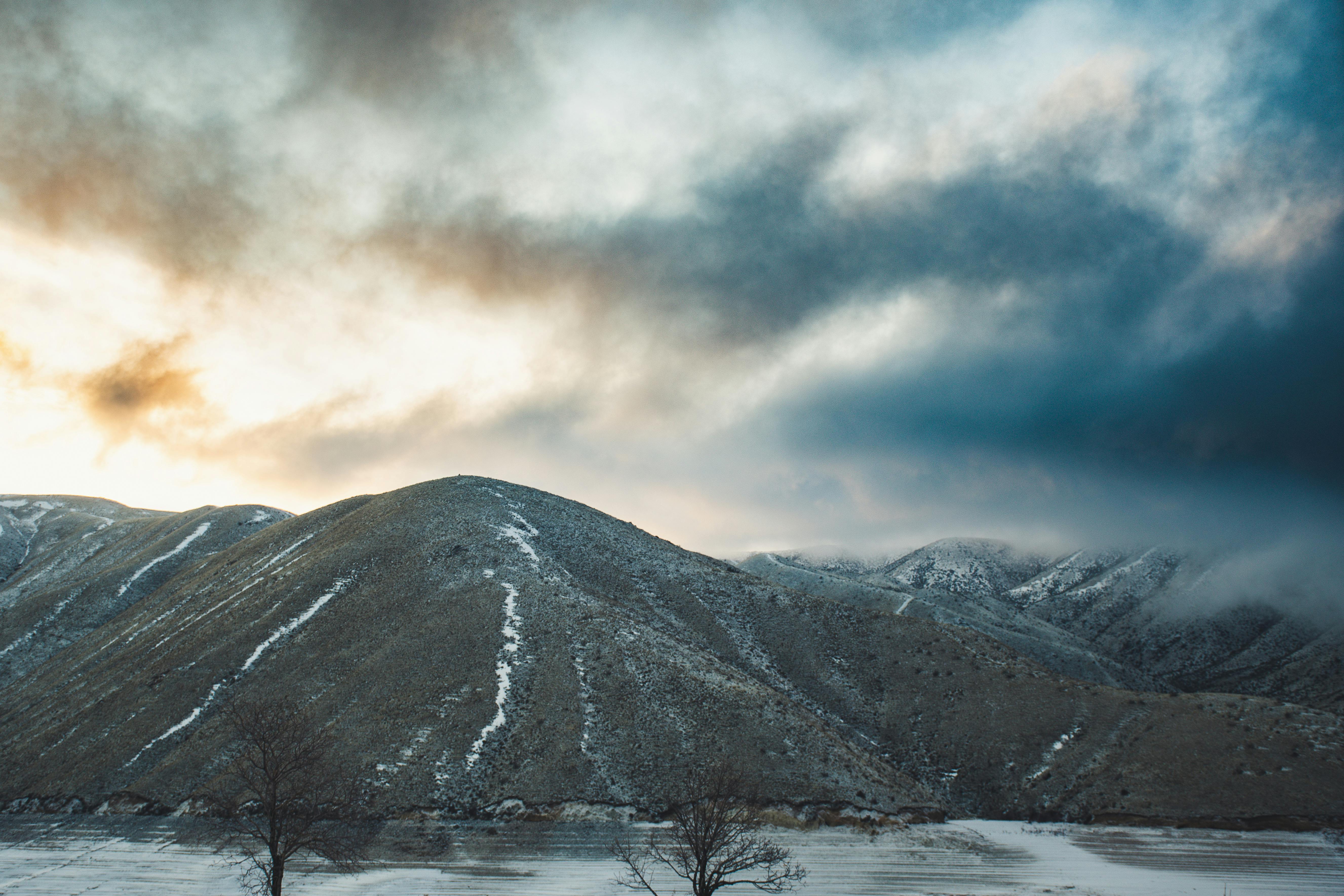 黎明时分，白雪皑皑的山脉在壮丽的云层下显得格外令人惊叹，尽显大自然的宁静之美