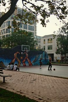 Children playing basketball on a vibrant court in urban Toronto, Canada.