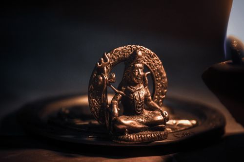 Free Intricate bronze sculpture of a Hindu deity illuminated by warm lighting, emphasizing traditional craftsmanship. Stock Photo