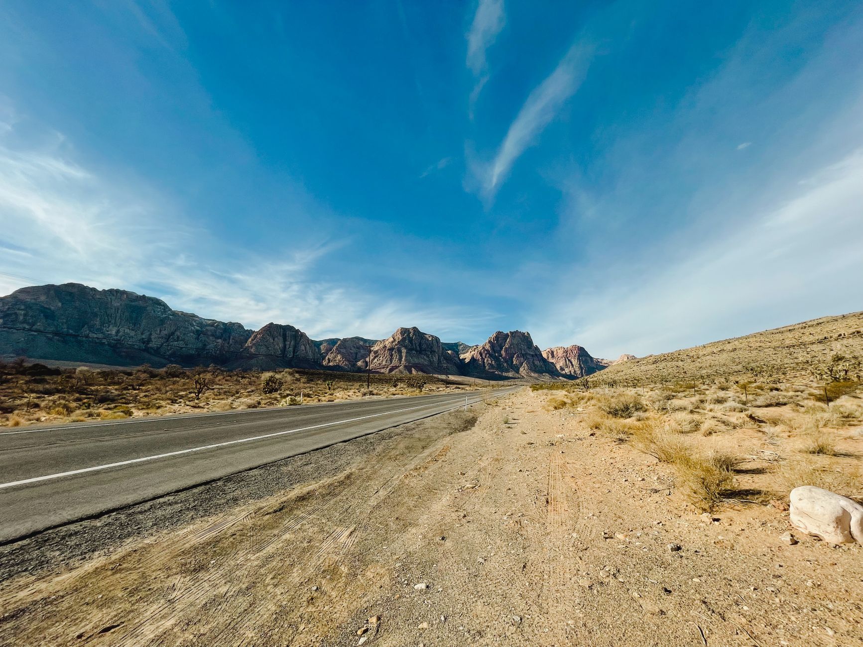Empty desert highway stretching to Nevada mountains