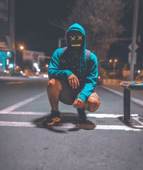 夜晚，一个戴着发光面具的神秘蒙面人蹲在城市街道上，营造出一种怪异而有趣的氛围