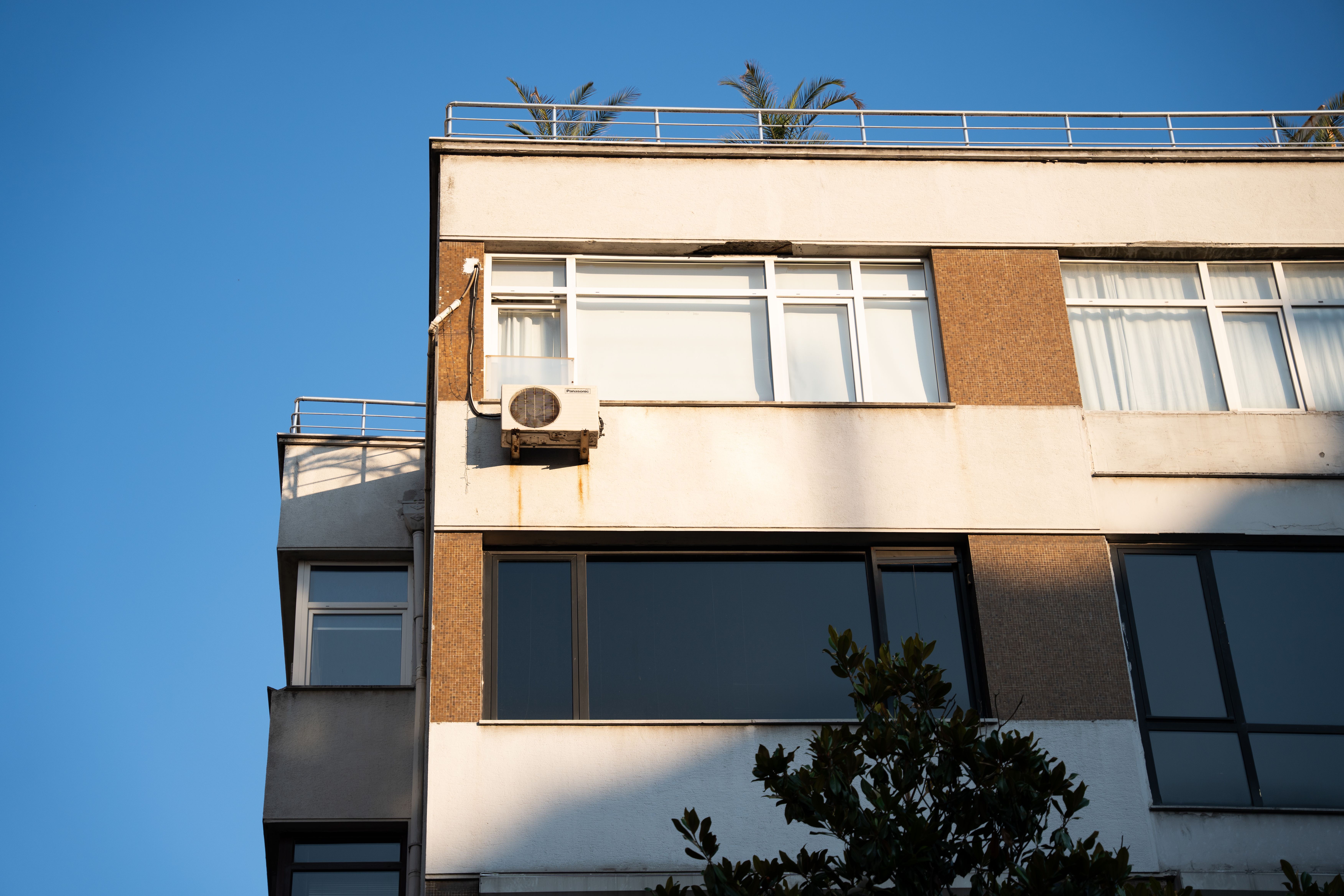 Air source heat pump mounted on a flat roof with pipework running to a parapet