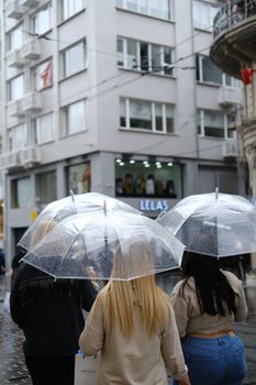 People walking with transparent umbrellas on a rainy city street. Urban life and weather.