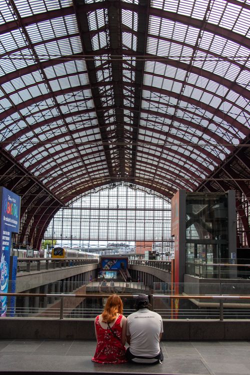 Free A couple sitting and waiting at Antwerp Central Station, highlighting its architectural beauty. Stock Photo