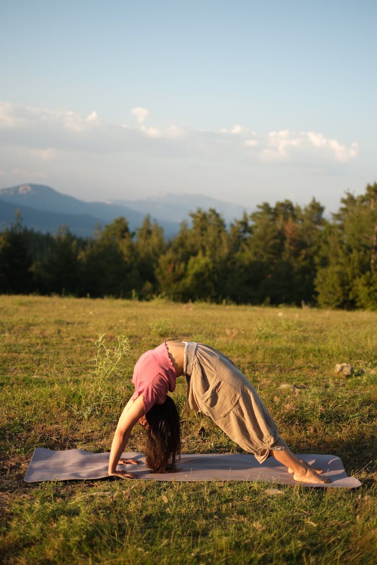 Woman Practicing Yoga On Grassland