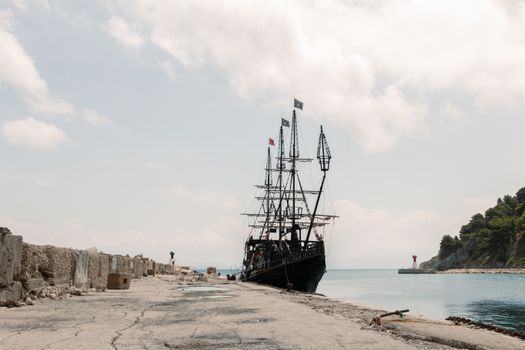 A classic vintage ship moored at Vlorë harbor with scenic coastal backdrop.