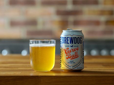 Brewdog Curve Ball West Coast IPA in a can with a chilled glass on a wooden table.